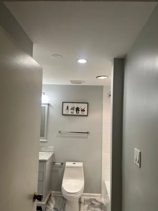 Finished bathroom with a new vanity, recessed lighting and a tiled shower