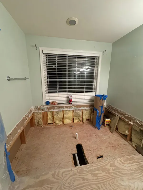 Bathroom walls and floor opened up, showing insulation and subfloor, during a remodel