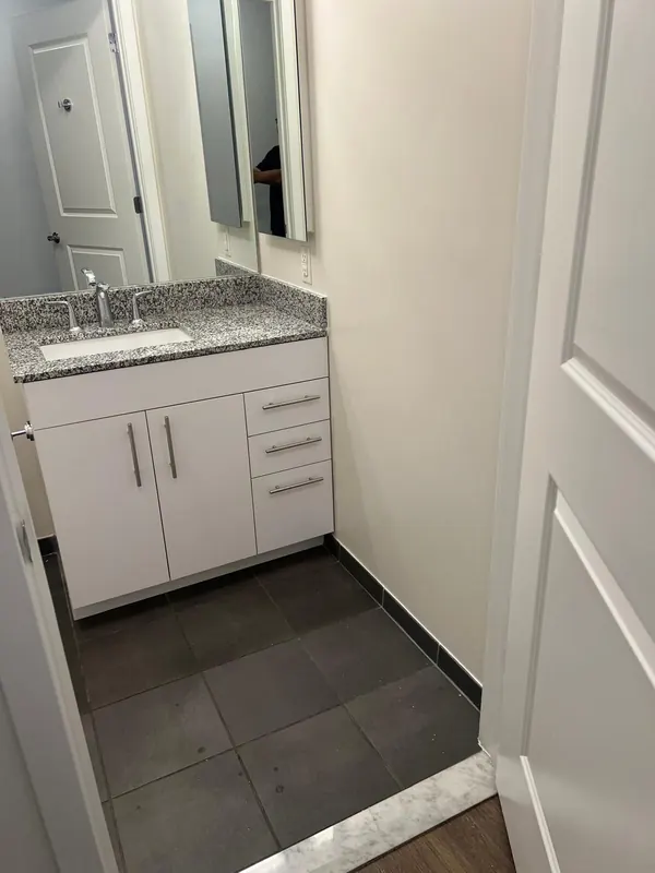 Bathroom vanity with a granite top and gray tile floor