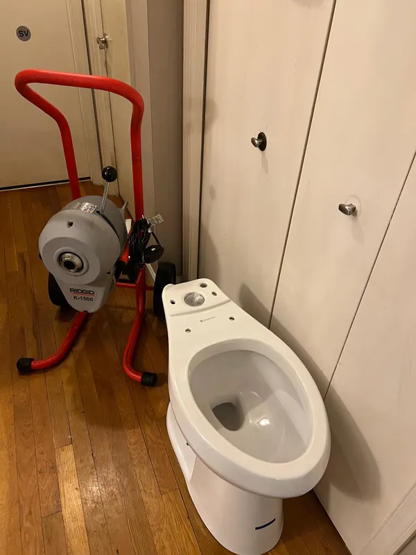 Drain cleaning machine set up beside a toilet