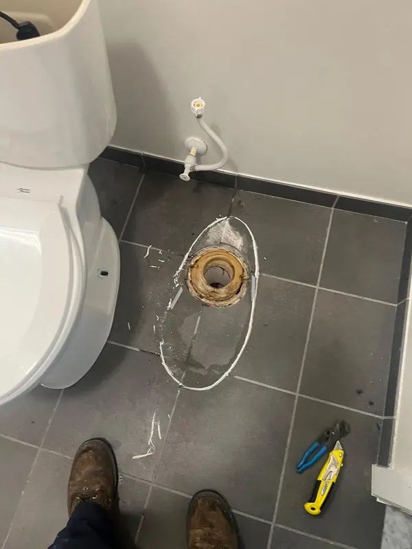 Toilet flange and cut tile on a bathroom floor during a repair