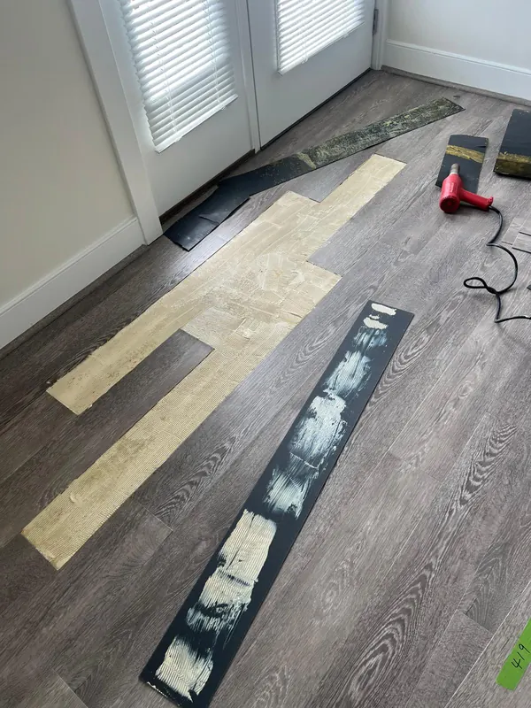 Vinyl plank flooring partly pulled up during a repair, with tools nearby